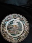 Prato decorativo em porcelana " Real"  com desenho de cena campestre com casarão vitoriano, borda com desenhos florais detalhados. Diam. 25 cm.