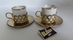 2 xícaras em porcelana na cor branca c/ friso dourado na borda " Vera Cruz". Acompanha suporte e pires na cor ouro c/ elegante cinzelado. Sem uso com etiqueta. Bijoux Montnhatre"