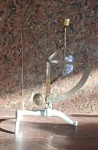 Pequena e antiga Balança de Ourives elaborada com metal dourado e base de alumínio. Med. Base 16cm e altura com 27cm