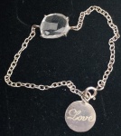 Pulseira infantil em prata sem contraste, com detalhe de uma pedra central e medalha escrito LOVE. Medindo 14 cm de comprimento aberta.