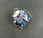 Lindo broche em metal dourado representando JOANINHA com pedrinhas na cor azul . Medindo aproximadamente 2 x 2 CM.