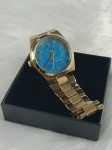MICHAEL KORS -  Relógio em tom dourado , com fundo do visor nas cores azul com leve rajado .Necessita de Bateria .