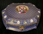 Excepcional Caixa de porcelana Francesa , em grandes proporções,  PORCELANA DE LIMOGES, porcelana francesa de "Limoges" no padrão "Sevres". Esmaltagem azul cobalto , profusamente embelezada com detalhes em ouro e realçados com ramos e flores. Tampa com "arranjo floral em reserva". Guarnição e fecho em bronze dourado . Circundada por guirlanda esmaltada em flores e damas antigas alternadas com medalhões em policromia, borda recortada, arrematada em bronze . Interior com flores em policromia. Medindo 42 x 32 x 20 cm. Marca no fundo.