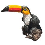 Escultura representando um pequeno tucano no tronco, confeccionado em resina, lindamente policromado nas cores naturais do animal. Medidas: Altura: 8,5 cm. Largura: 5 cm. Comprimento: 11 cm.