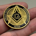 Moeda em metal dourado, com referência à maçonaria. Medindo 4 cm de diâmetro. Na caixinha de acrílico.