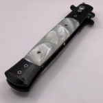 Canivete em aço anodizado, na cor preta, trava de segurança, lâmina de metal e com detalhe no estilo madrepérola. Medindo aberto 23 cm.