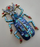 Exuberante broche em metal representando BESOURO todo trabalhado em pedrinhas , esmaltada , nos tons azuis e vermelho. . Medindo 8X5 .Linda peça.