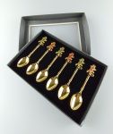 Seis colheres em metal dourado com pega representando lagarto policromado . Peças na caixa original .