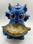 Incensário cascata em resina policromada, moldada como dragão baby na cor predominante azul. Incenso é colocado na parte superior da cabeça com a fumaça exalando pelo nariz. Medidas: Altura 12cm x Largura 10cm x 11cm Profundidade.