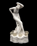 Escultura em porcelana Europeia, representando Figura feminina Semi Nua, com bolas de cristal em sua base, medindo 19 cm de altura.