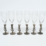 Conjunto de 6 Taças de cristal, marcado, com pés em metal com figuras nuas, medindo 21 cm de altura.