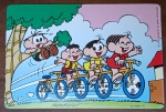Cartões Postais promocionais Nestlé / Turma da Mônica (1995). A cena é dinâmica e divertida, mostrando Mônica, Magali e Cascão em uma bicicleta de três lugares (tandem), enquanto o Cebolinha tenta acompanhá-los em um skate de madeira.