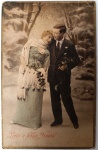 Antigo Cartão Postal Italiano "Lieto e felice Natale"  Casal em Paisagem de Inverno  Fotografia Colorizada (Circa 1910-1920)Raro cartão postal antigo de origem italiana, celebrando o Natal ("Lieto e felice Natale"  Alegre e feliz Natal). A peça apresenta uma estética refinada, típica das produções fotográficas de estúdio europeias do início do século XX, que buscavam retratar o ideal de felicidade e elegância da época