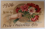 Antigo Cartão Postal "1906"  Relevo Dourado e Cromolitografia  Mensagem Manuscrita de Época Raríssimo cartão postal de Ano Novo datado de 1º de Janeiro de 1906. Esta peça é um exemplo primoroso da era de ouro dos cartões postais, destacando-se pelo uso de múltiplas técnicas de impressão e acabamento artístico que visavam criar um objeto de desejo e coleção