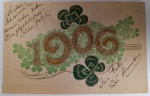Antigo Cartão Postal "1906"  Relevo Dourado e Cromolitografia  Símbolos de Sorte (Trevos) e Manuscrito AlemãoRaríssimo exemplar de cartão postal de Ano Novo datado de 1906. Esta peça é um documento único, contendo uma carinhosa mensagem manuscrita em alemão de um pai para seu filho, o que a torna um item de alto interesse para colecionadores de história social e genealogia.