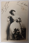 Antigo Postal Fotográfico 1905  Atriz "Quéder"  Fotografia Real Belle ÉpoqueRetrato artístico da modelo/atriz Quéder. Ela veste um traje de gala ornamentado com flores escuras, múltiplas pulseiras e uma pose elegante característica dos cartões-postais franceses de celebridades do período.