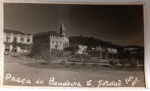Antigo Cartão-Postal Campos do Jordão (SP)  Praça da Bandeira  Circa 1950Registro histórico da Praça da Bandeira em Vila Abernéssia, núcleo administrativo de Campos do Jordão. É possível ver a arquitetura típica da época, a torre da igreja e o relevo montanhoso com araucárias ao fundo.