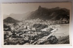 Antigo Postal Fotográfico Rio de Janeiro  Vista Aérea Botafogo e Corcovado  Circa 1960 Imagem panorâmica capturada a partir do Morro da Urca ou Pão de Açúcar. Em primeiro plano, a Enseada de Botafogo e o bairro da Urca; ao fundo, a silhueta imponente do Corcovado com a estátua do Cristo Redentor. Um registro da era de ouro do turismo carioca.