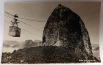 Antigo Postal Fotográfico Rio de Janeiro  Bondinho e Morro do Pão de Açúcar  Circa 1950Impressionante vista lateral do Morro do Pão de Açúcar com a cabine histórica do bondinho em suspensão. Ao fundo, as montanhas da cidade e a Baía de Guanabara. Um registro clássico do cartão-postal mais famoso do Brasil.