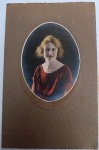 Magnífico retrato de estúdio de uma jovem, apresentando técnica de colorização manual em tons de vermelho e dourado. A fotografia está montada em um suporte original de cartão rígido com textura "marroquim" e moldura oval decorativa em relevo.