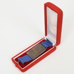 NUMISMÁTICA, uma (1) medalha uniface, Conselho das Associações e Entidades de S. Cristóvão  Reconhecimento, confeccionada em metal prateado, medindo 45 x 30 mm mais fita na tonalidade azul, acondicionada em estojo, vide foto.