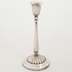 METAL PRATEADO, um (1) castiçal com fuste na forma de cone, esferas de amarração, bobeche em tulipa, base canelada, sem marca de manufatura aparente, medindo 24 cm altura, sinais de uso, vide foto.