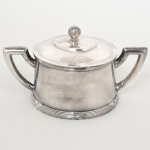 METAL PRATEADO, um (1) açucareiro da marca WOLFF (tradição desde 1894), ornamentação no padrão Império napoleônico com frisos intercalados por X, pega da tampa esférica, medindo 9 cm altura, sinais de uso, vide foto.