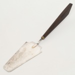 FAQUEIRO, uma (1) espátula para bolo, confeccionada em metal prateado, cabo em madeira maciça, marca REGÊNCIA, medindo 28 cm comprimento, sinais de uso, vide foto.