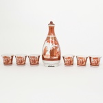 PORCELANA, conjunto para saquê com sete (7) itens: 1 garrafa com tampa e 6 copinhos, ornamentação pintada a mão em tons de vermelho, representando cena do gênero, paisagem, elementos vegetalistas e geométricos, marca de origem KUTANI em caracteres estilizados no fundo da garrafa, copinhos trazem no fundo o rosto de uma gueixa na técnica LITHOPHANE (técnica de modelagem em espessuras variadas, quando iluminadas por traz formam uma imagem; inventada pelos Chineses no século XV conhecida como AN-HUA que significa secreto ou decoração oculta; a partir de 1760 Worcester, empregou técnica similar em suas porcelanas; muito tempo depois o diplomata francês Barão Paul de Bourgoing a patenteou em 1827, cujo os primeiros exemplares foram produzidos pelo seu amigo o Barão Alexis du Tremblay, em uma cerâmica na região de Rubelles e marcadas AdT; em 1829 Meissen começou a produzir sob licença de Bourgoing; além de muitas outras como: Berlim; Plaue; Volkstedt; São Petersburgo; Royal Copenhagen; etc.; em meados do século XX a técnica foi muito difundida no Japão), medindo respectivamente 16 cm e 4 cm altura, sinais de uso, vide foto.