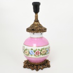 LUMINÁRIA, um (1) abat-jour, base com bojo em porcelana, pintado a mão com flores em policromia, faixas na tonalidade rosa, arremates a ouro, monture em bronze vazado em elementos vegetalistas, medindo 31 cm altura, parte elétrica funcionando, sinais de uso, vide foto.