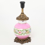 LUMINÁRIA, um (1) abat-jour, base com bojo em porcelana, pintado a mão com flores em policromia, faixas na tonalidade rosa, arremates a ouro, monture em bronze vazado em elementos vegetalistas, medindo 31 cm altura, parte elétrica funcionando, sinais de uso, vide foto.