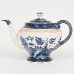 FAIANÇA JAPONESA, um (1) bule com tampa, ornamentação WILLON (Segundo a lenda chinesa: Um certo Mandarim tinha uma leal e devotada filha, possuidora de rara beleza. Certo dia, em que descobre que ela estava apaixonada por um carteiro que lhe fazia a corte, e que era por ela correspondida, expulsa a filha de casa e roga-lhe uma praga: que ao ser trocado o primeiro beijo pelo casal, eles se transformariam em dois pombos), também conhecida como pombinhos, tonalidade azul sobre fundo branco, arremates a ouro, possui manchas e o craquejado característico do envelhecimento de toda a faiança, marca N. K. T. - Imperial Ironstoneware, Made in Japan, medindo 15 cm altura, sinais de uso, vide foto.
