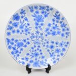 PORCELANA, um (1) medalhão decorativo, pintado a mão na técnica blue and white, representando flores, Assinado IOLANDA, marca PORCELANARTE (empresa de decoração em porcelana de outras fábricas, funcionou nas décadas de 60/70 em Campo Largo, PR), medindo 32 cm diâmetro.