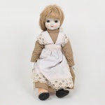 BRINQUEDO, uma (1) boneca com cabeça, mãos e pés em biscuit, corpo em tecido com enchimento, vestes em tecido, sem marca de manufatura aparente, medindo 43 cm altura, vide foto.