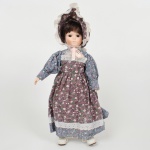 BRINQUEDO, uma (1) boneca com cabeça, mãos e pés em biscuit, olhos de vidro fixos, corpo em tecido estampado, sem marca de manufatura aparente, medindo 39 cm altura, vide foto.