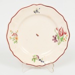 FAIANÇA FRANCESA, um (1) prato para sobremesa com ornamentação floral e inseto, policromado, borda recortada, ínfima trinca na borda, marca SARREGUEMINES (Fundada em 1790 por Nicolas-Henri Jacobi; em 1800, Paul Utzschneider assumiu a fábrica e começou sua expansão; em 1836 seu filho Alexandre Geiser assume a gestão; em 1871 Paul Geiser filho de Alexandre Geiser assume a gestão e veio a falecer em 1913 e a empresa Porzellanfabrik Utzschneider & Cie se dividiu em 2 (dois) empreendimentos: um em Sarreguemines e o outro em Digoin e Vitry-Le-Francois; em 1919 foram unidas novamente sob o nome Sarreguemines-Digoin-Vitry-Le-Francois e administradas pela família Cazal; entre 1942 e 1945 em virtude da Segunda Grande Guerra a gestão foi feita pela Villeroy & Boch; em 1978 foi comprada pela Lunéville-Badonviller-Saint-Clement; em 1979 a produção de louças foi interrompida e retomada em 2002; em 2007 foi liquidada por Ordem Judicial), modelo STRASBOURG, medindo 20,5 cm diâmetro, vode foto