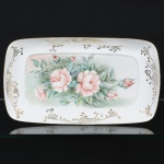 PORCELANA, uma (1) travessa, quase retangular, pintada a mão com rosas em policromia, arremates a ouro, Atelier IOLANDA 1971, marca SCHMIDT (Pomerode, SC; Mauá, SP; Campo Largo, PR, fundada em 1945, ainda em atividade, maior fábrica de porcelana da América Latina), medindo 36 x 20 cm, vide foto.