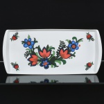PORCELANA, uma (1) bandeja quase retangular, ornamentação floral policromada, dita bordado com flor (típica do povo polonês), manufatura SCHMIDT (Pomerode, SC; Mauá, SP; Campo Largo, PR, fundada em 1945, ainda em atividade, maior fábrica de porcelana da América Latina), medindo 40,5 x 19 cm, vide foto.