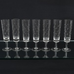 VIDRO, sete (7) flutes de pé alto para champanhe ou espumante, incolores e translúcidos, bojo quase cilíndrico, lapidado em esferas espaçadas, fuste cilíndrico, base em bolacha, medindo 18 cm altura, sinais de uso, vide foto.