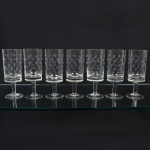 VIDRO, sete (7) taças de pé alto para vinho tinto, incolores e translúcidos, bojo quase cilíndrico, lapidado em esferas espaçadas, fuste cilíndrico, base em bolacha, medindo 15,5 cm altura, sinais de uso, vide foto.