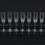 CRISTAL, sete (7) flutes de pé alto para champanhe ou espumante, fuste quase cilíndrico continuação do bojo, base em bolacha, manufatura STRAUSS marcada em acidado na base, medindo 21,5 cm altura, vide foto.