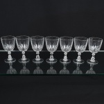 DEMI CRISTAL, sete (7) taças de pé alto para vinho branco, incolores e translúcidas, bojo ligeiramente obcônico, terço inferior moldado em sulcos, fuste hexagonal na forma de coluneta, base em bolacha, medindo 12,5 cm altura, sinais de uso, vide foto.