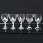 DEMI CRISTAL, cinco (5) taças de pé alto para vinho branco, incolores e translúcidas, bojo ligeiramente obcônico, terço inferior moldado em sulcos, fuste hexagonal na forma de coluneta, base em bolacha, medindo 12,5 cm altura, sinais de uso, vide foto.