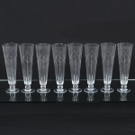 VIDRO, oito (8) flutes , incolores e translúcidos, para cerveja ou espumante, fuste quase esférico, base em bolacha, bojo com singela lapidação em sulcos e esferas, medindo 22,5 cm altura.