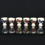 FAIANÇA, seis (6) porta ovos, ornamentação floral policromada pintada a mão, arremates a ouro, sem marca de manufatura aparente, possuem bicadinhos e trincas, vide foto.