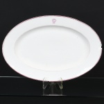 PORCELANA, uma (1) antiga travessa oval, marca possessória monogramada representada pelas letras CP, ornada com frisos na tonalidade magenta, trincas e bicados na borda, medindo 50 x 34 cm, sem marca de manufatura aparente, sinais de uso, vide foto.