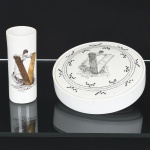 PORCELANA, dois (2) itens distintos com ornamentação policromada representando dama segurando livro que forma a letra V, sendo: 1 vaso floreiro cilíndrico, medindo 13 cm altura; 1 tampa com recipiente adaptado, medindo 16 cm diâmetro, Atelier YVETTE 76, vaso com marca quase apagada da PORBRAS (Guarulhos, SP, anos 60 até 1991), sinais de uso, vide foto.