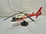 Maquete, miniatura decorativa em metal de helicóptero modelo Airbus/Eurocopter Dauphin, com pintura nas cores vermelho e creme, inscrição PR-SEG e logomarca Senior Táxi Aéreo, montado em base Helimaquetes, peça detalhada e de caráter não funcional, ideal para coleção ou decoração. Medindo 39cm x 19cm de altura.