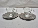Par de xícaras de café em vidro com pires em aço inox, peça da Nespresso. Medindo 6cm x 6,5cm de altura.