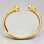 PANTHÈRE - Pulseira rígida em ouro 18k, estilo Thomas Cartier, com exuberantes cabeças de felinos cuidadosamente trabalhadas, cravejadas com 112 brilhantes (full cut) no total (56 em cada extremidade), representando aproximadamente 2.24 Ct. Presença de olhos em esmeraldas lapidadas. Peça de alta joalheria com engenhoso dispositivo de abertura assimétrica por pressão. Peça de desenho Art Deco inspirado na célebre linha francesa dos anos 30 conhecida como; Panthère. Excelente presença e acabamento. Peso total 25,27 g.